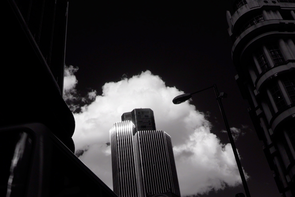 An infrared picture of Tower 42 with white clouds and a black sky